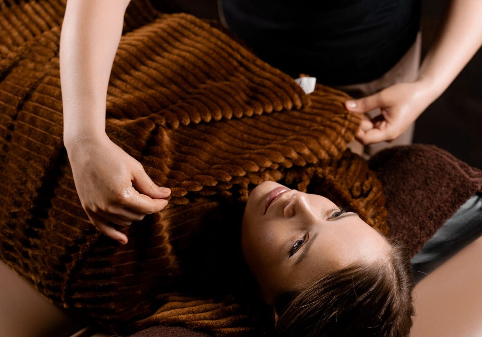 Person lying under brown textured blanket